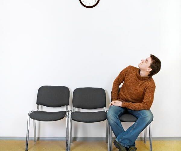 Man sitting in a waiting room looking at a clock