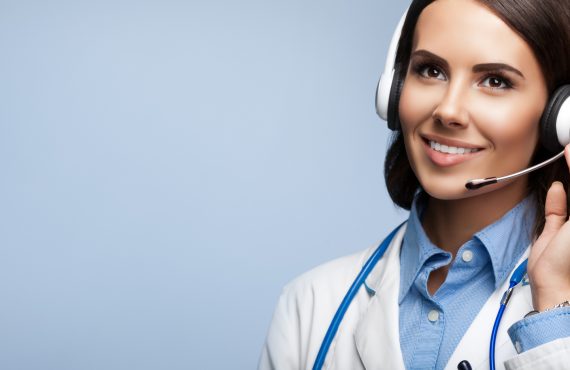 Portrait of happy smiling young medical answering assistant in headset, on grey background