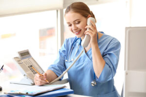 Young medical assistant talking to a patient on phone in a healthcare clinic